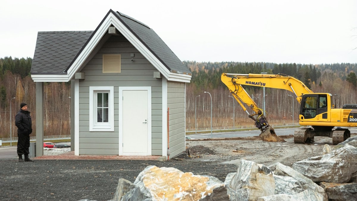 white and blue wooden house near yellow and black excavator during daytime