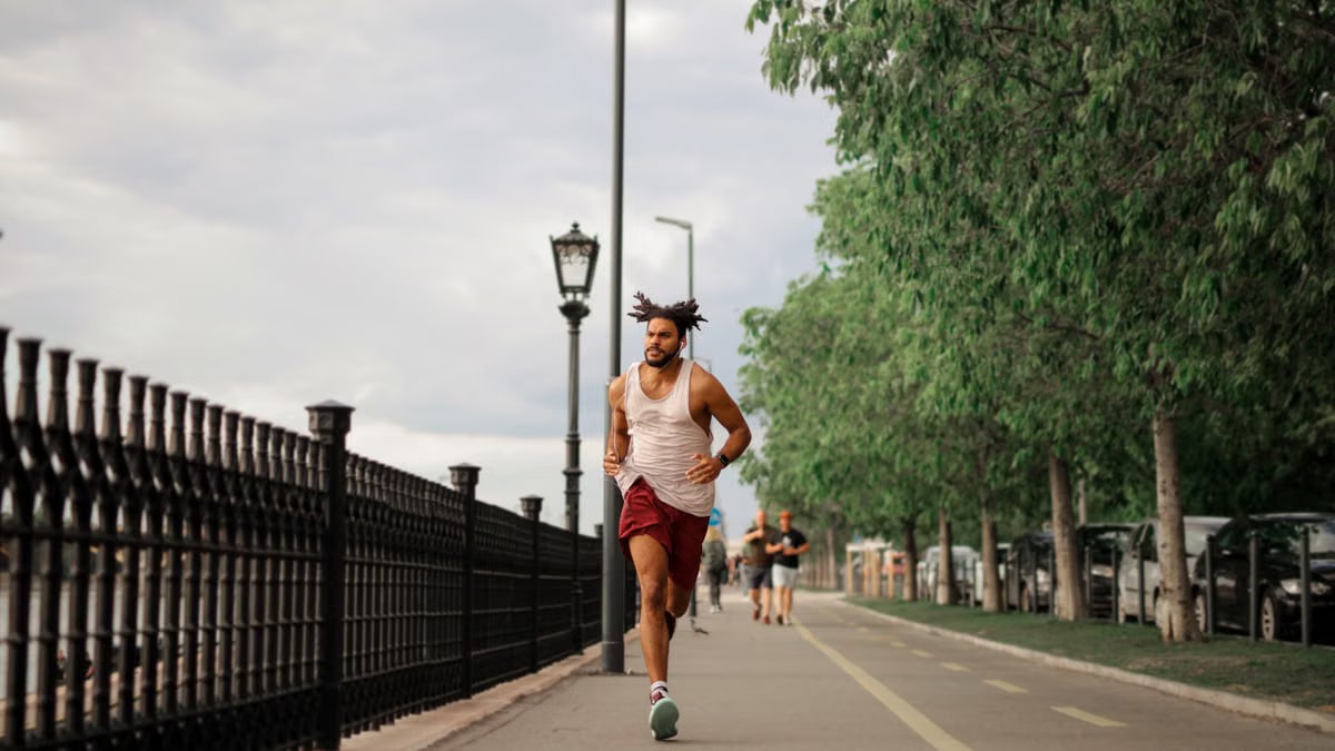 Man jogging along a city street with trees, promoting a healthy and active lifestyle.